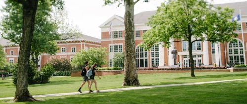 Students walking on the ý campus in front of Crounce Hall